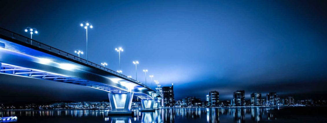 bridge-at-night-with-the-lights-on-across-river-1024x374